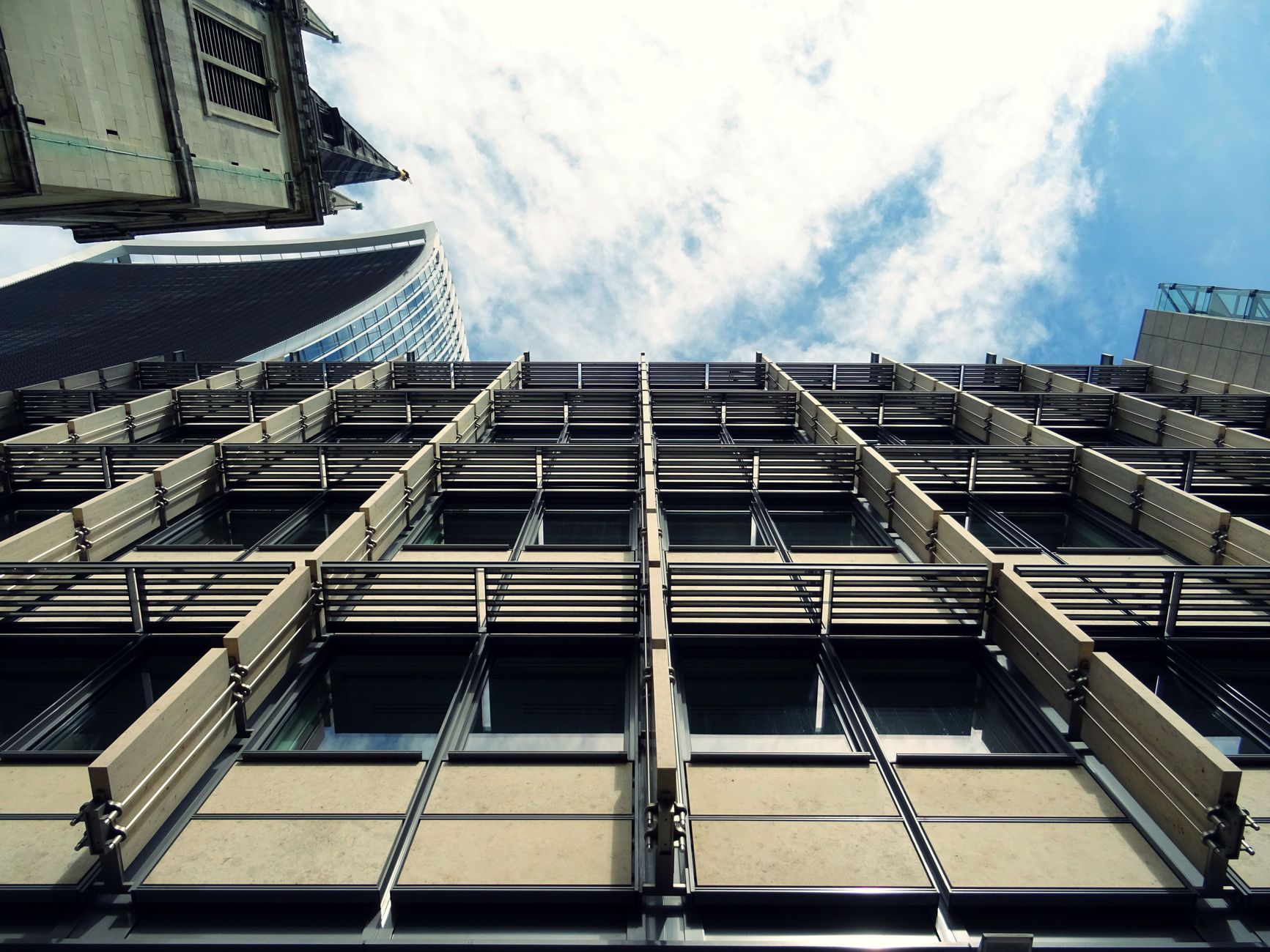 Low-angle view of a modern urban skyscraper with glass windows and abstract architectural design.