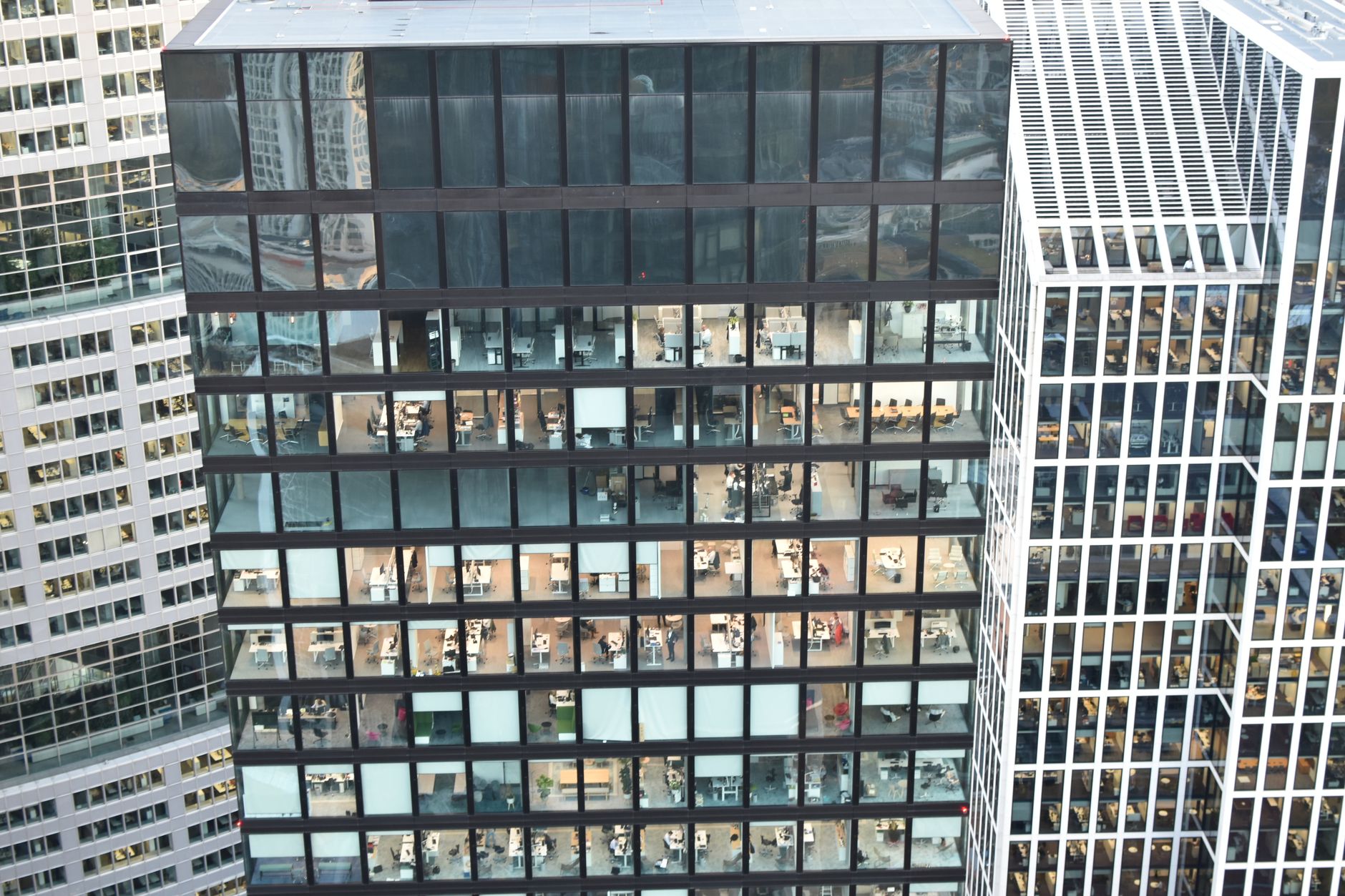 High-rise building facade with visible office interiors, showcasing urban architecture.