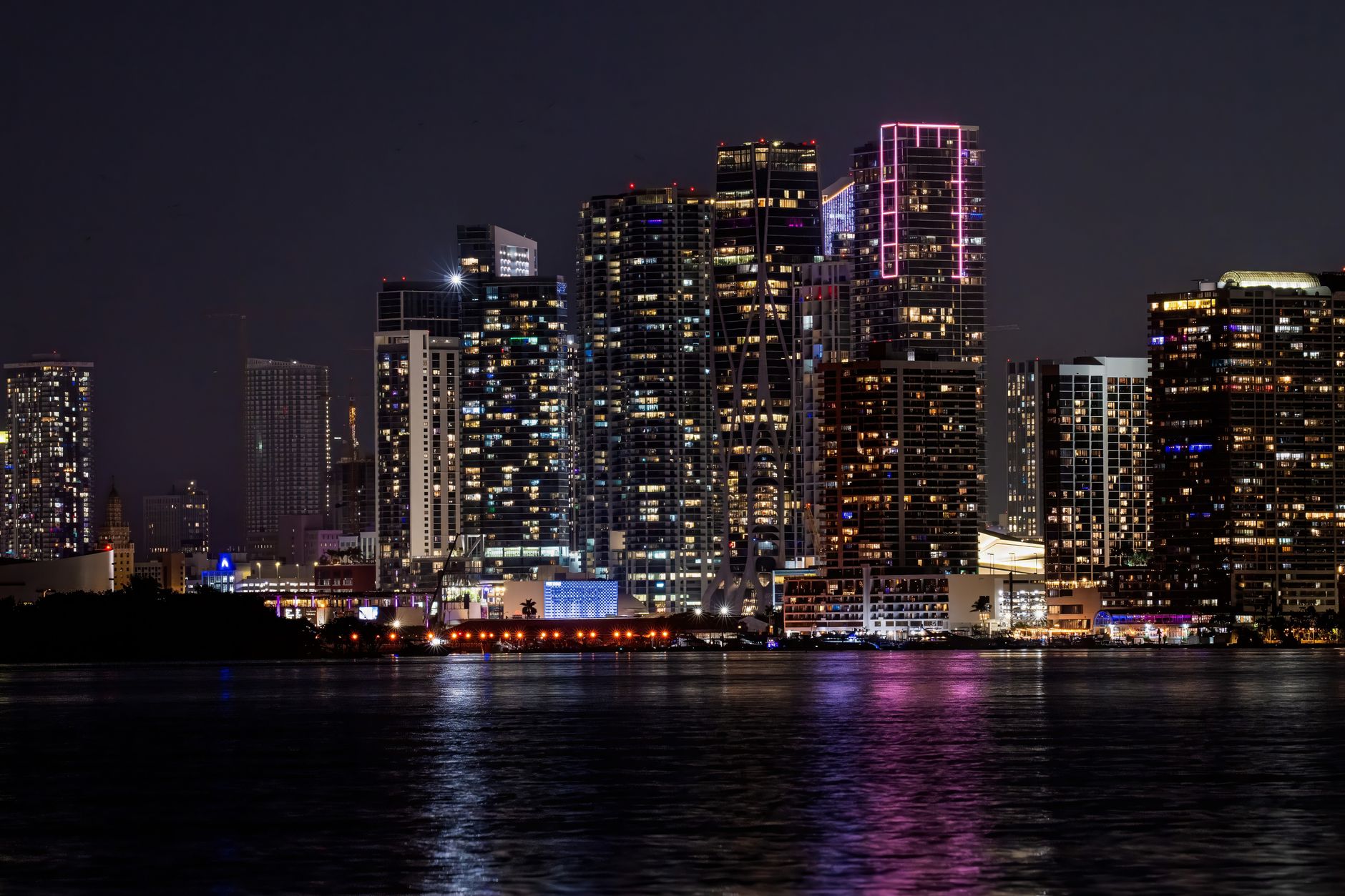 A stunning view of Miami's illuminated skyline reflecting on water at night.