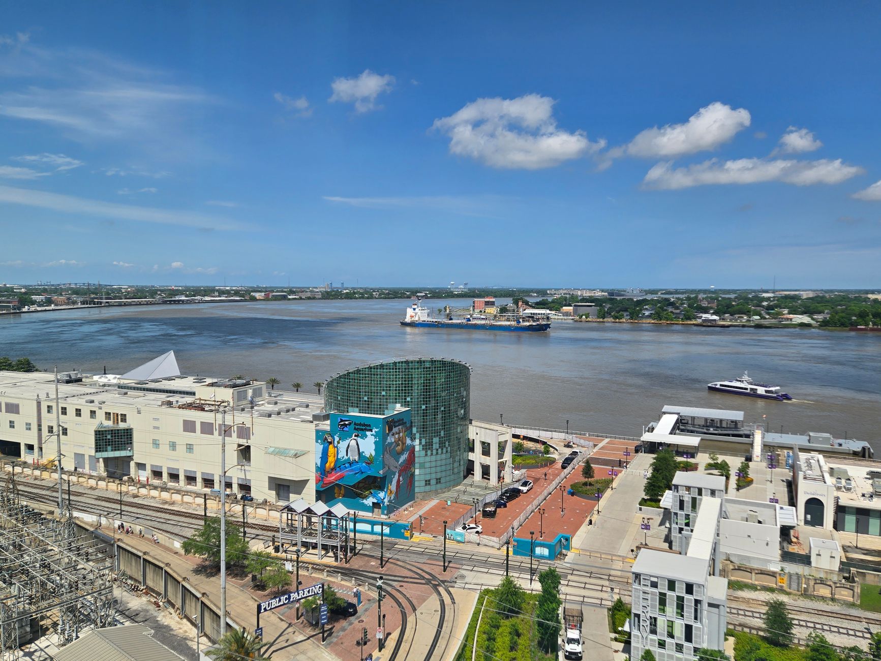 Scenic aerial view of the Mississippi River and New Orleans cityscape with boats and urban buildings.